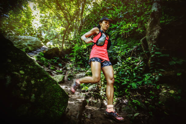 mujer corredora de maratón de ultra trail corriendo cuesta abajo a través de la selva tropical - carrera de campo través fotografías e imágenes de stock