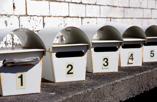 Detail of a row of white metal letterboxes mounted on a concrete wall