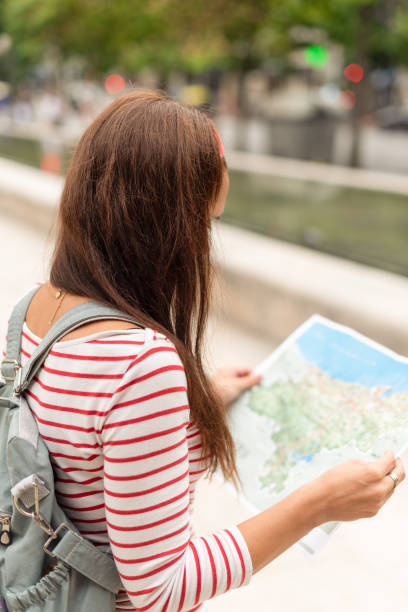 istock Anonymous woman with backpack and map in city 1367277497