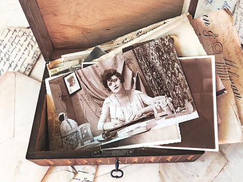Vintage photographs and letters inside an old wooden box surrounded by old open letters . High-view-angle image of photographs and letters from the beginning of the 20th century.