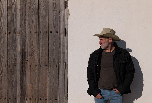 Portrait of adult man in cowboy hat and jeans against wall. Almeria, Spain