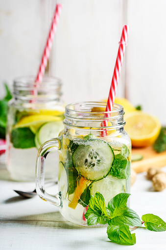 Detox drink with water, cucumber, lemonade and mint in mason jar glass with retro straws.