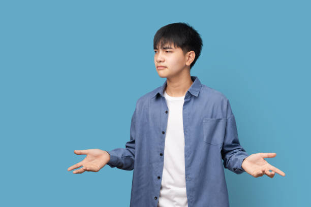 I don't know, Puzzled and clueless young handsome Asian man with arms out. stock photo