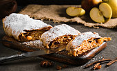 Apple pie - strudel or apfelstrudel, sliced pie with apples and spices on a gray table, close-up, selective focus. Traditional pies of European cuisine