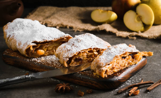 Apple pie - strudel or apfelstrudel, sliced pie with apples and spices on a gray table, close-up, selective focus. Traditional pies of European cuisine Apple pie - strudel or apfelstrudel, sliced "u200b"u200bpie with apples and spices on a gray table, close-up, selective focus. Traditional pies of European cuisine strudel stock pictures, royalty-free photos & images