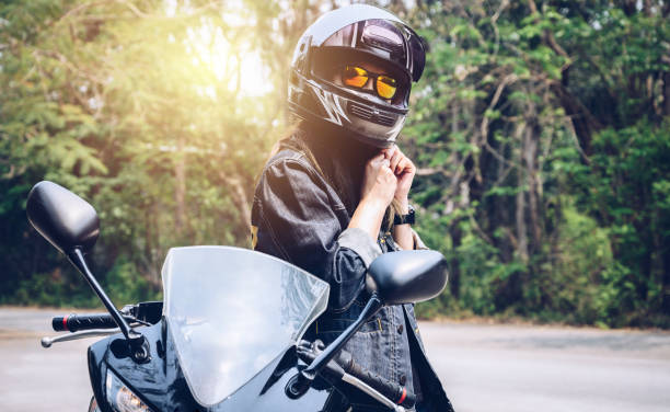 Confidence Asian woman wearing a motorcycle helmet before riding. Helmets contribute to motorcycle safety by protecting the rider's head. motorcycles stock pictures, royalty-free photos & images