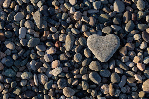 Heart shaped stone on pebble beach. Concept