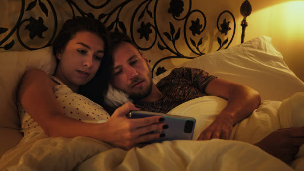 istock Young couple watching movie in bed. Using smart phone and getting bored 1367287891