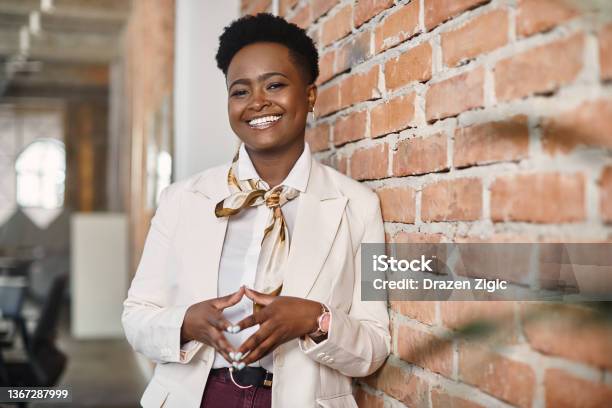 Confident Black Businesswoman Leaning On A Wall In The Office And Looking At Camera Stock Photo - Download Image Now