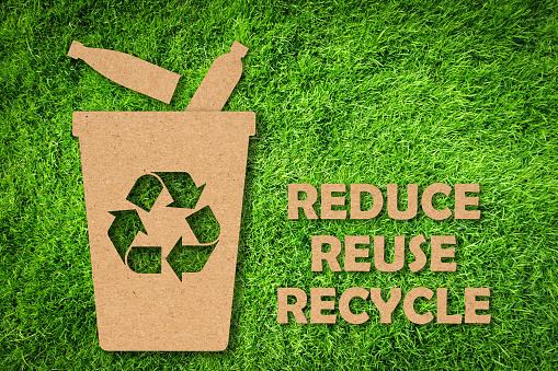 Corte de papel Kraft de Reutilizar, Reducir, Reciclar símbolo y texto sobre fondo de hierba verde. Concepto de conservación ambiental. photo