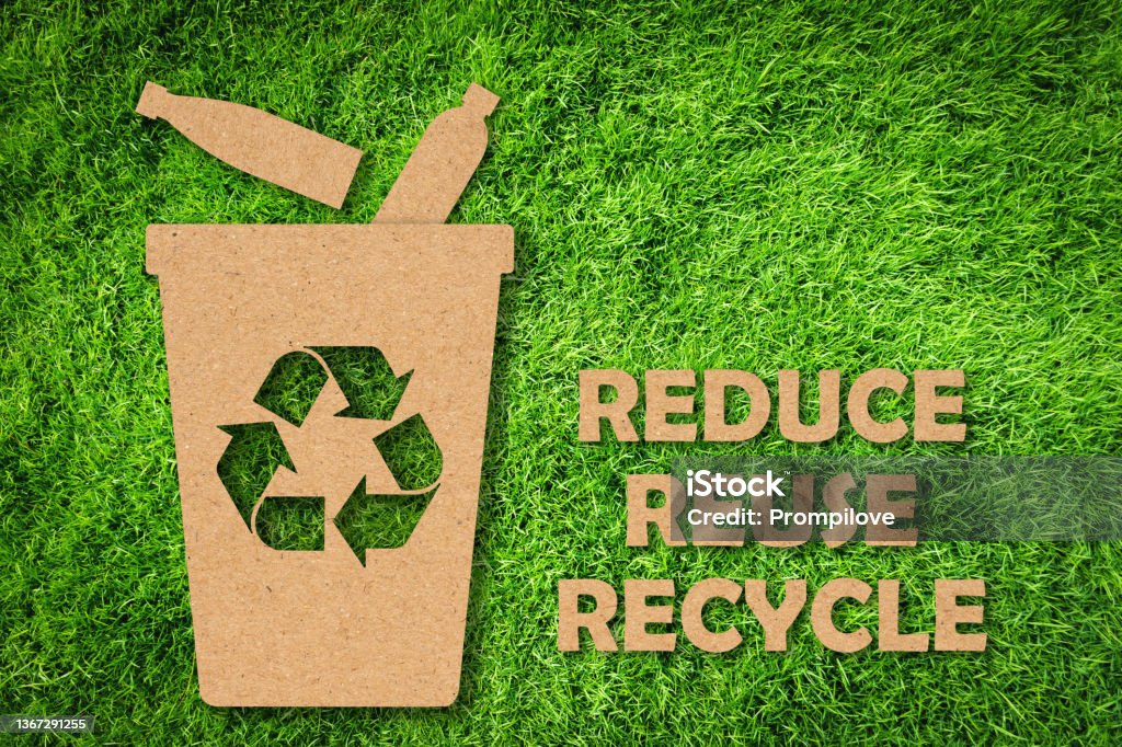 Kraft paper cut of Reuse, Reduce, Recycle symbol and text on green grass background. Environmental conservation concept. Kraft paper cut of Reduce, Reuse, Recycle symbol and text on green grass background. Environmental conservation concept. Recycling Stock Photo