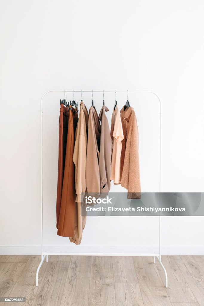 Beige capsule of clothes on a rack over white background Capsule of casual clothes beige color palette hanging on a rack over white background Fashion retail concept Space Capsule Stock Photo