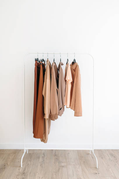 Beige capsule of clothes on a rack over white background stock photo
