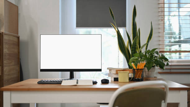istock Front view computer, coffee cup, pencil holder and house plant on wooden table at home office. 1367292581