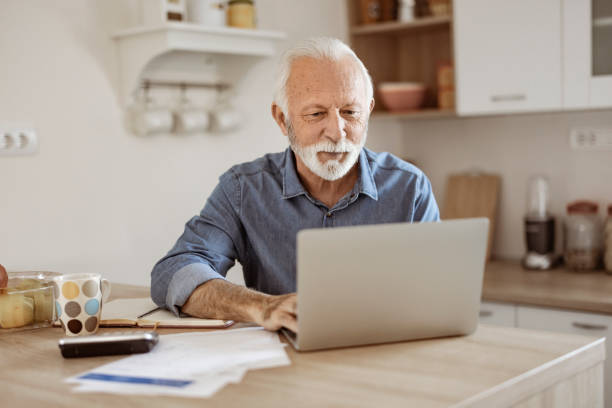 istock Senior Man at Home in Front of Laptop Computer Working 1367292944