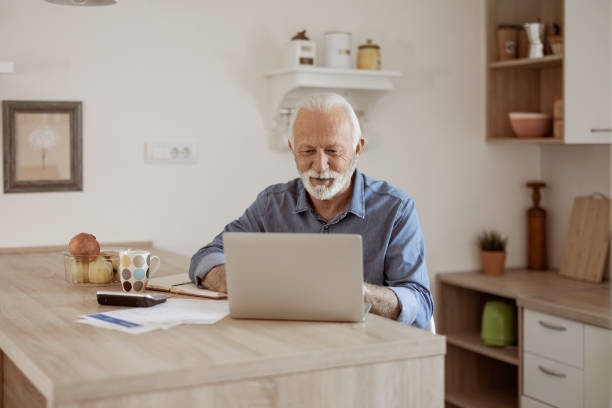 istock Senior Man at Home in Front of Laptop Computer Working 1367293050