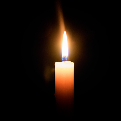 the flame of a candle burning in the dark.