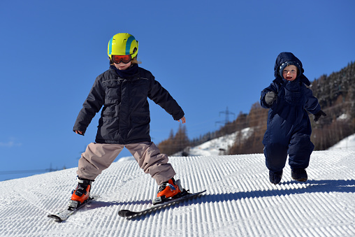 Young girl skiing and having fun with her little brother in the beginners area in the ski resort of St .Anton am Arlberg, Austria