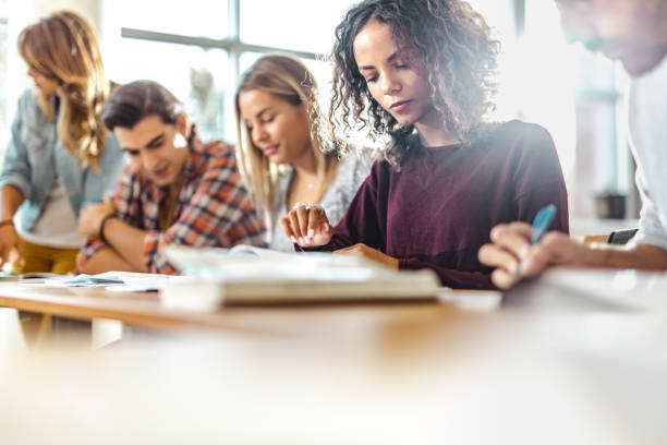 istock Concentrated college student reading a book on a class. 1367296112