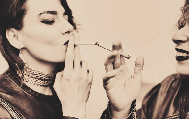 두 명의 청녀가 서로에게 담배에 빛을 줍니다. - friendship women two people sensuality 뉴스 사진 이미지