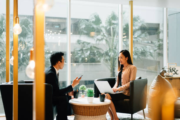 istock Two Asian white collar workers having discussion in lounge area 1367301638