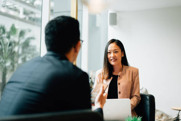 Two Asian white collar workers having discussion in lounge area stock photo