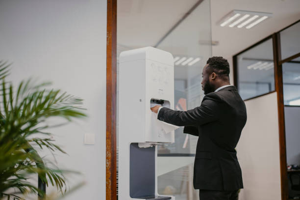 istock Businessman using hand sanitizer station in office 1367302244