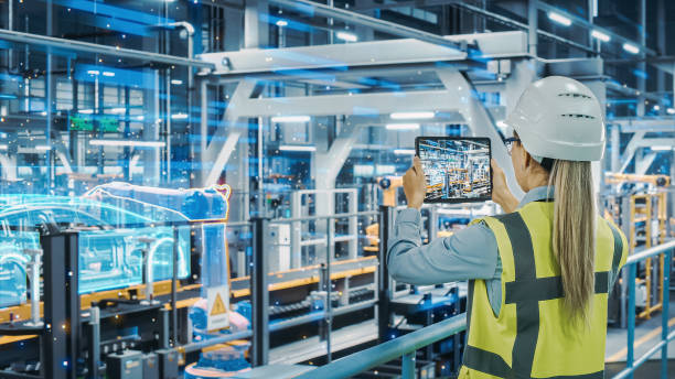 istock Futuristic Car Factory Digitalization Industry 4.0: Female Automotive Engineer Using Augmented Reality Tablet Computer to Scan Automated Robot Arm Assembly Line Manufacturing Electric Vehicles 1367303226