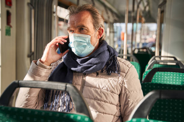 istock Mature man wearing protective mask sitting at the train and having conversation 1367306510