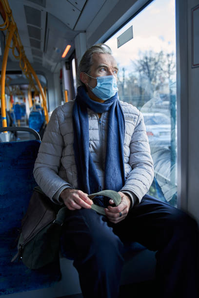 istock Senior passenger wearing protective mask looking at the window at public transport 1367306556