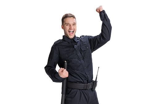 Wow emotions. Studio shot young happy man, policeman officer wearing black uniform posing isolated on white background. Concept of job, caree, law and order. Security service. Copy space for ad