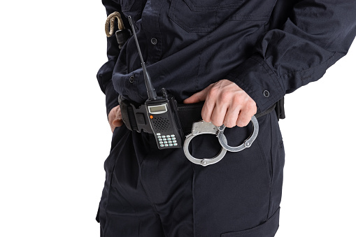 Cropped image of male policeman officer wearing black uniform with walkie-talkie and handcuffs isolated on white background. Concept of job, caree, safety. Security service. Copy space for ad