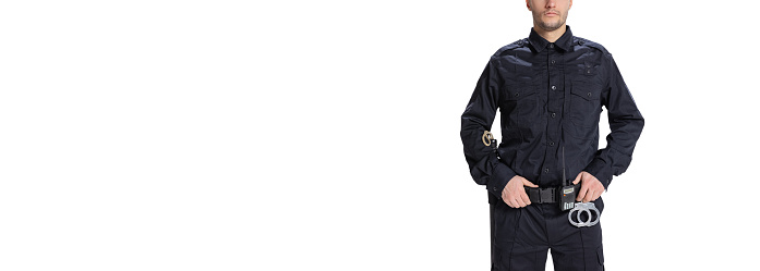 Flyer. Cropped image of male policeman officer wearing black uniform with walkie-talkie and handcuffs isolated on white background. Concept of job, caree, safety. Security service. Copy space for ad