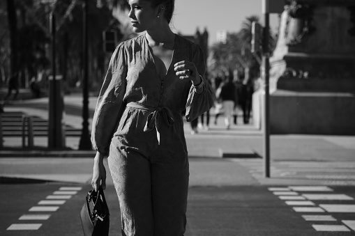 Close up gorgeous woman confidently crossing the road along street. Black and white photo