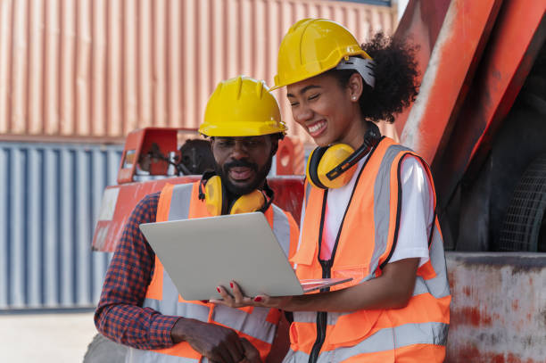 istock Engineering businessman and businesswoman holding laptop computer with container ship 1367307823
