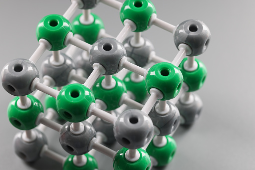 Plastic model of a molecule, crystal lattice of an atom on a gray background, close-up. Organic chemistry