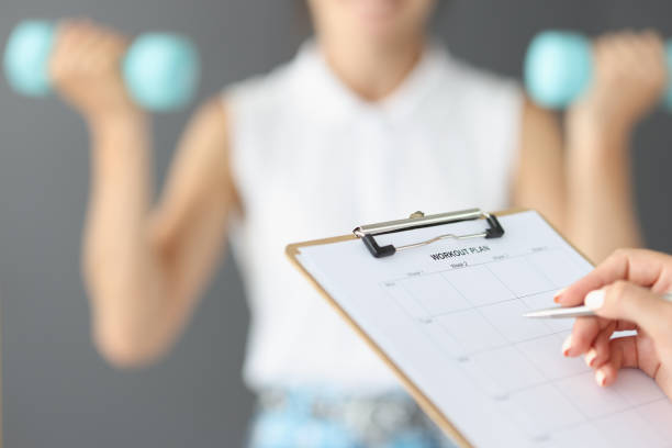 le mani femminili stanno scrivendo un piano di allenamento, motivazione - dieting planning calendar event foto e immagini stock