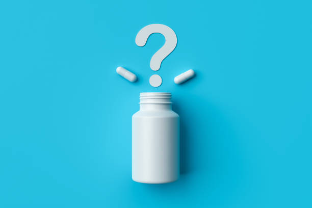 istock Plastic medical container and white capsule pills with question mark on blue background top view. 1367316535