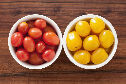 Top view of two bowls side by side with red and yellow cherry tomatoes