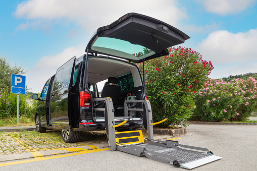 Accessible van with wheelchair lift ramp for person with disability.