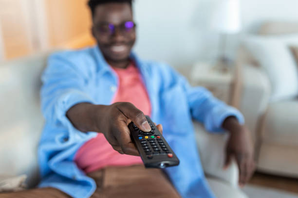 istock Excited African American Man Pointing Television Controller To Camera Switching Channels Watching TV . Television Programming Advertisement. Selective Focus 1367321172