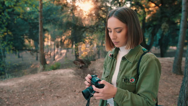 Girl rewinding analog camera film in the forest. Medium shot, fixed shot.