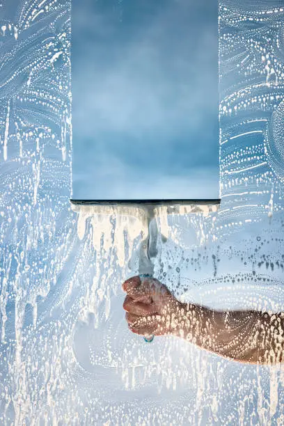 Photo of Window cleaner using a squeegee to wash a window