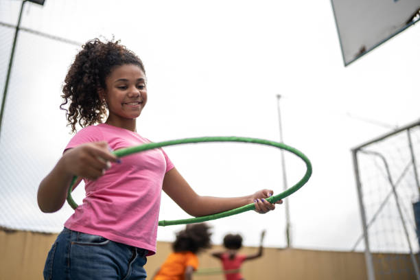 chica jugando con hula hoop en una cancha deportiva - hooping fotografías e imágenes de stock