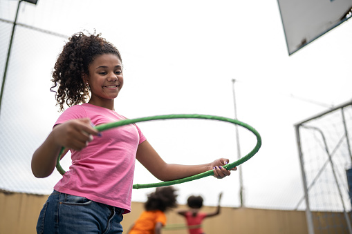 Girl playing with hula hoop at a sports court