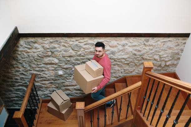 istock Young man carrying cardboard boxes for moving 1367328433