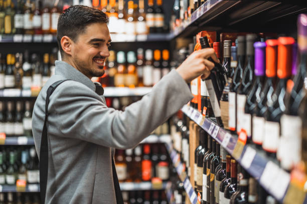 porträt einer lächelnden gutaussehenden, die im supermarkt eine weinflasche in der hand hält - wine wine bottle drink alcohol stock-fotos und bilder