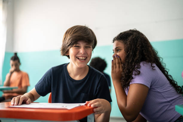 istock Girl whispering on a boy's ear in the classroom 1367329358