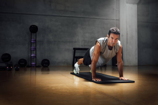 istock Strong caucasian man does push-ups while looks at camera in a dark gym. 1367329639