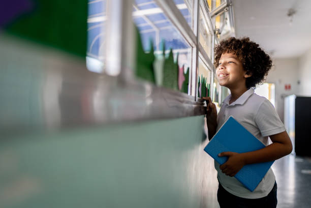 istock Boy looking through the window at school 1367329655